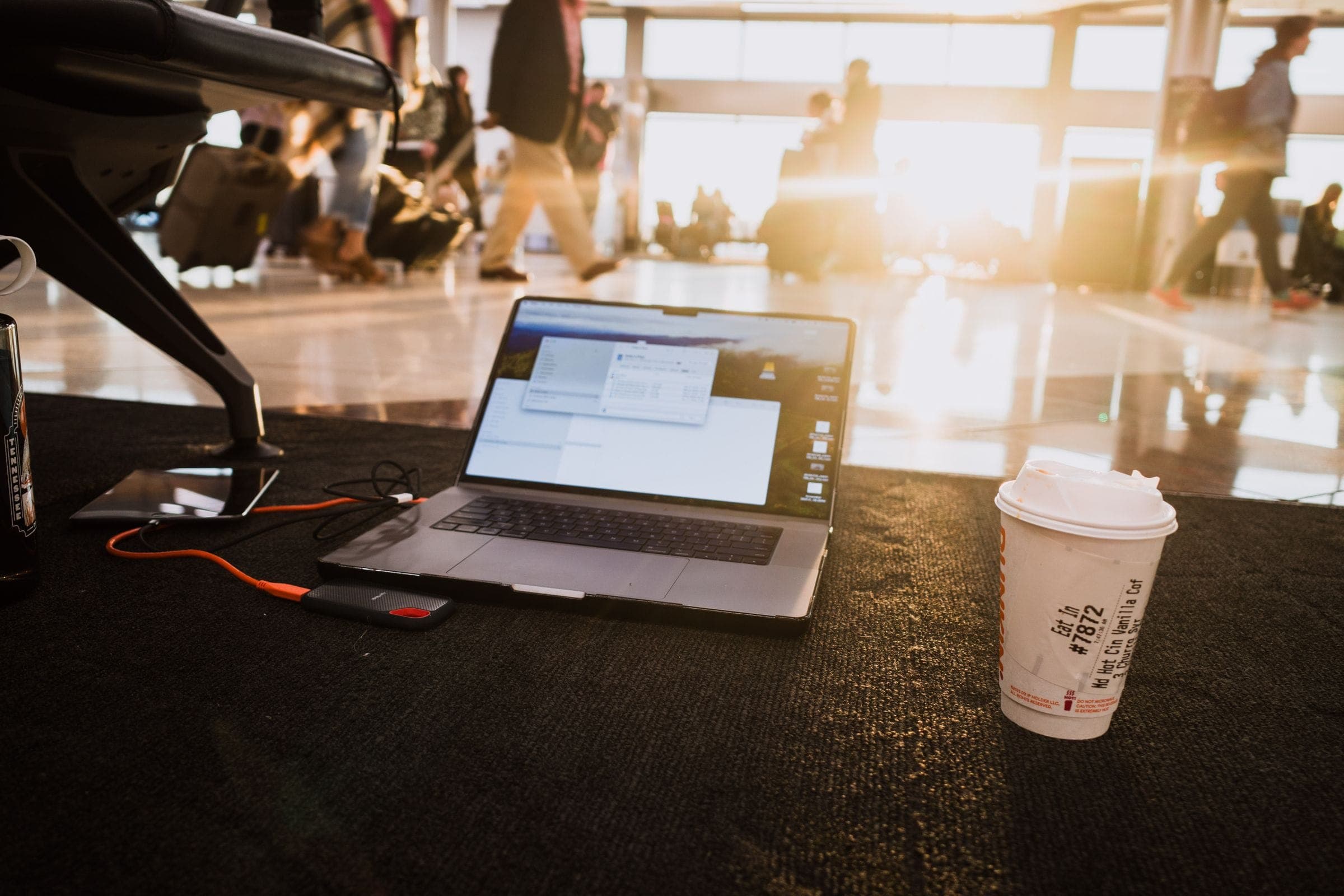 Laptop en koffie op een tafel in een zonnige luchthavenlounge